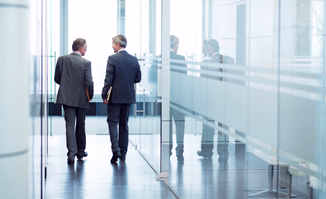 Two Businessmen Walking Down Office Building Hallway