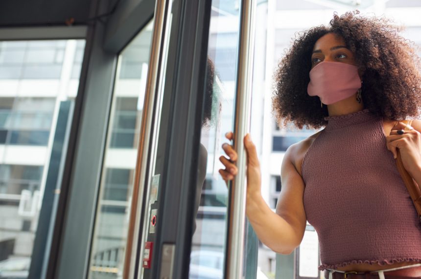 Young adult woman entering office wearing face mask looking off camera